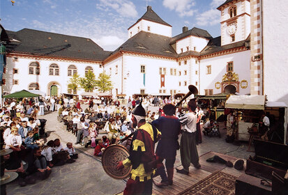 Foto eines Schlossfestes mit einer Rittervorführung auf der Bühne.