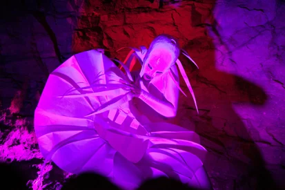 Foto einer Aufführung: eine weiße Figur im pinken Licht.