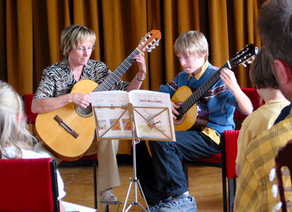 Foto einer Frau und eines Jungen an ihrer Gitarre.